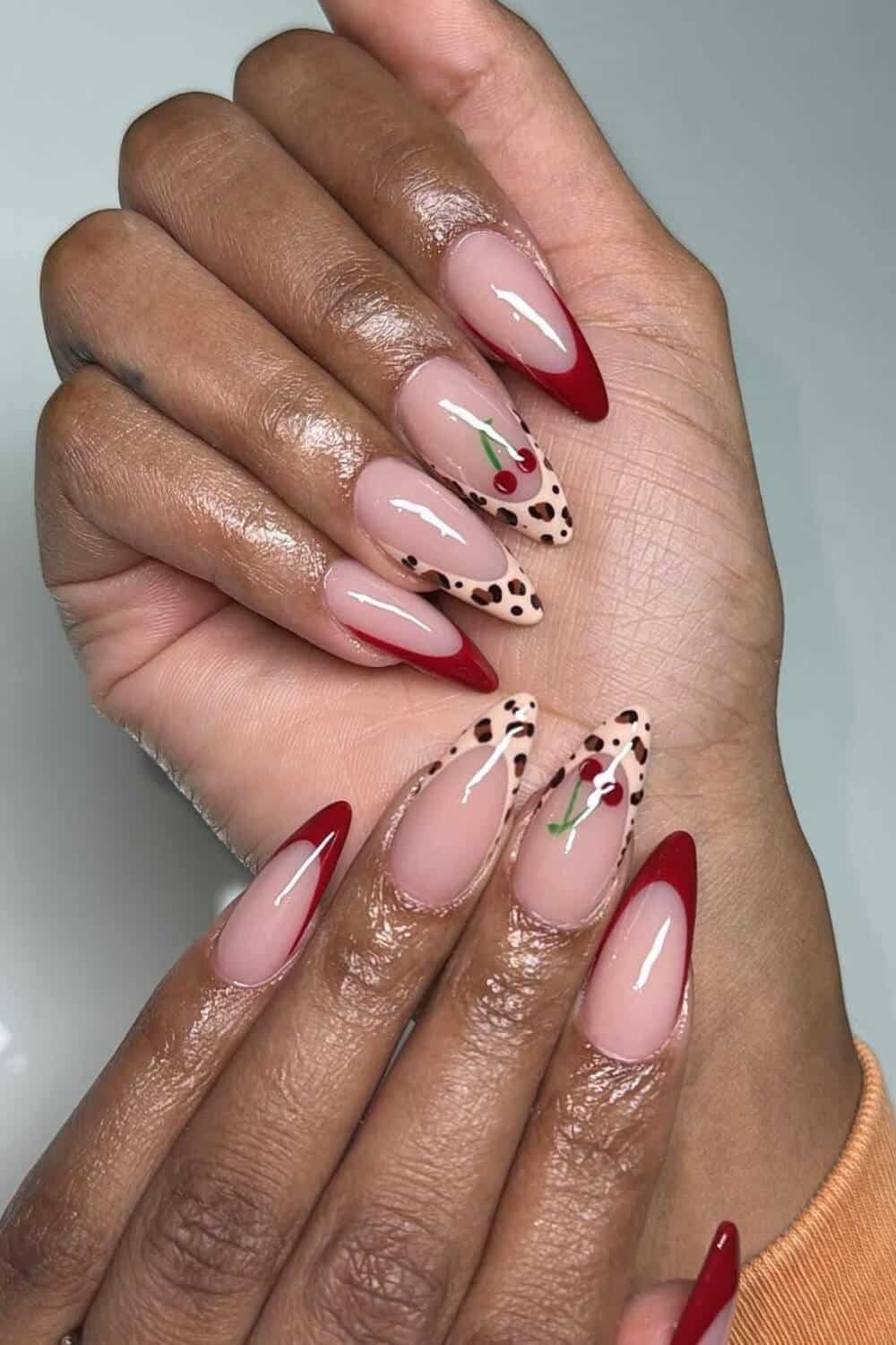 black woman's hands showing cherry red french nails with cheetah prints on the middle and ring finger