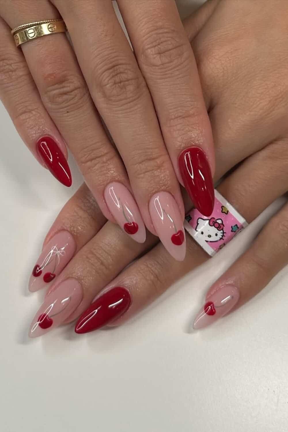 hands showing beautifully designed coquette cherry red nails with hello kitty bandaid on the ring finger