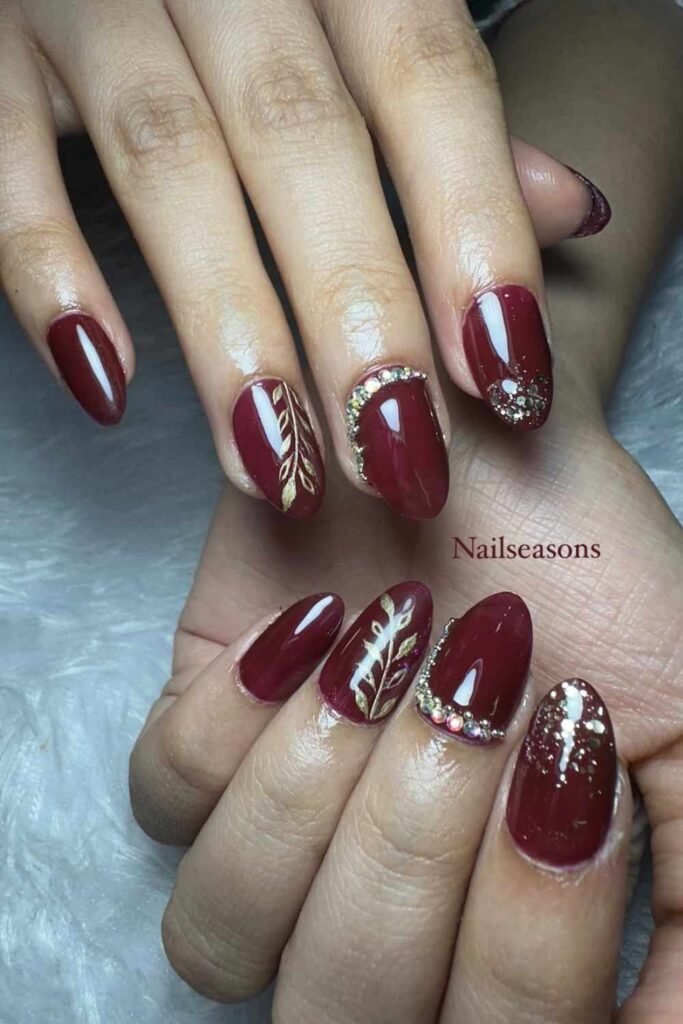 Wine-colored nails with gold foil accents, an elegant and bold choice for Indian or cultural bridal looks.
