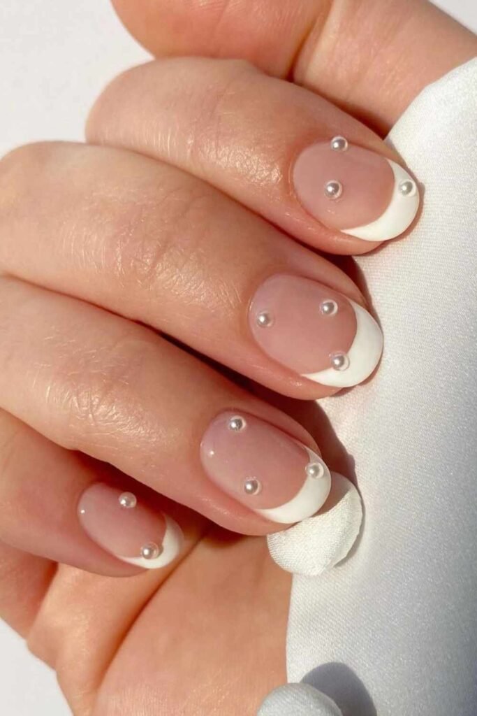 Short natural nails with soft French tips and dainty pearl details for a simple wedding nail design.