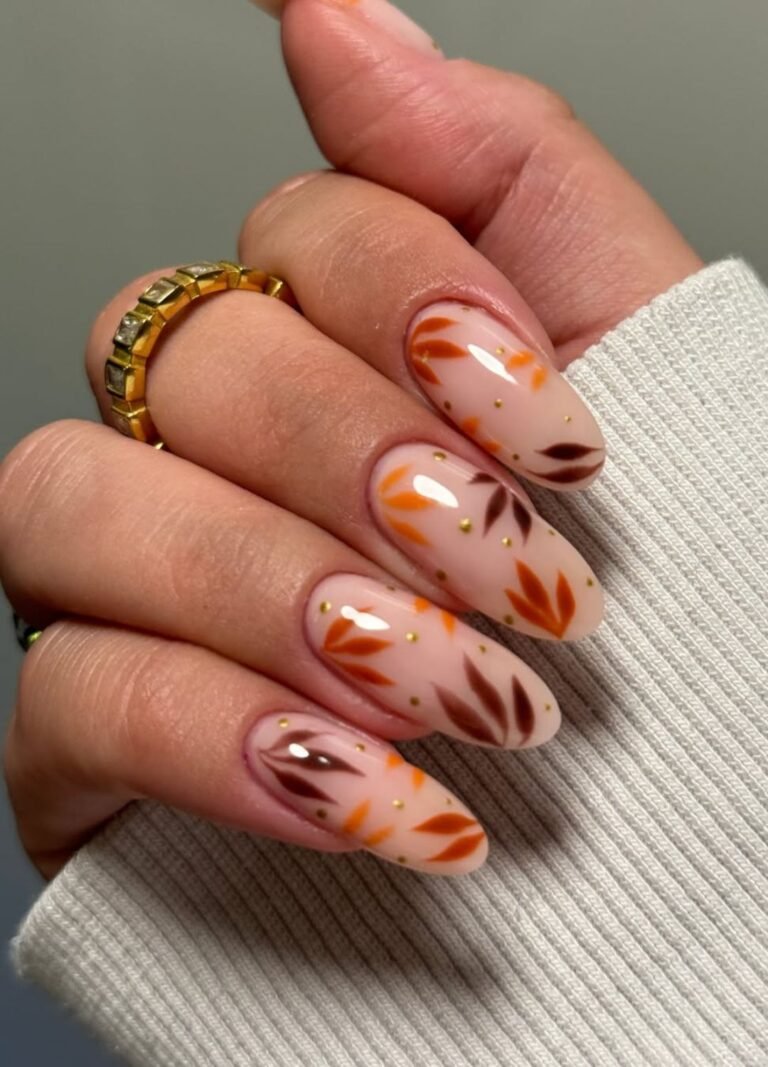 This design mixes warm oranges, browns, and cranberry red in delicate leaf patterns with golden dots all on a nude base. 
