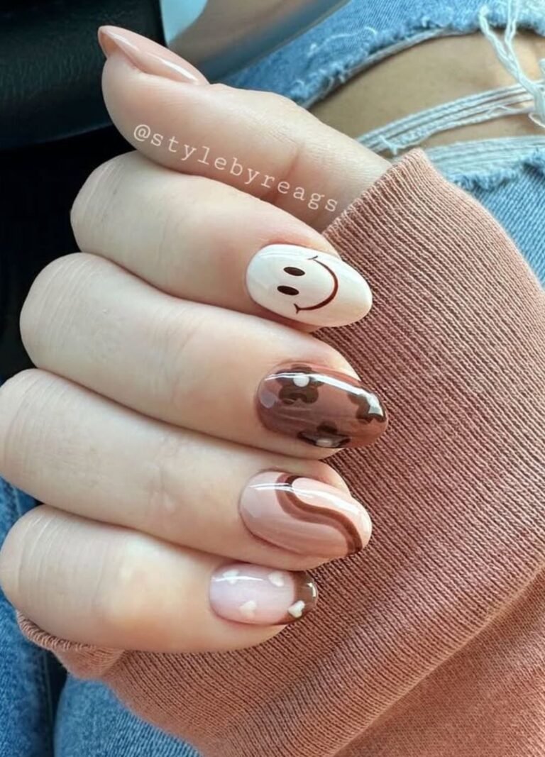 Playful meets seasonal with love with these brown nails! Smiley face, swirly accents, a warm brown fall floral, and creamy hearts on a brown French tip add fun personality to your mani