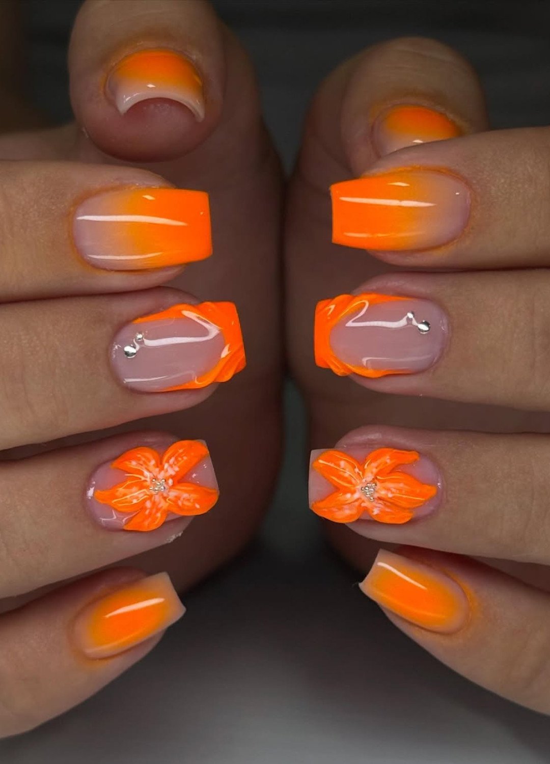hand display of Neon ombre blends eye-catching orange nails, added 3D flowers and patterns with glitter