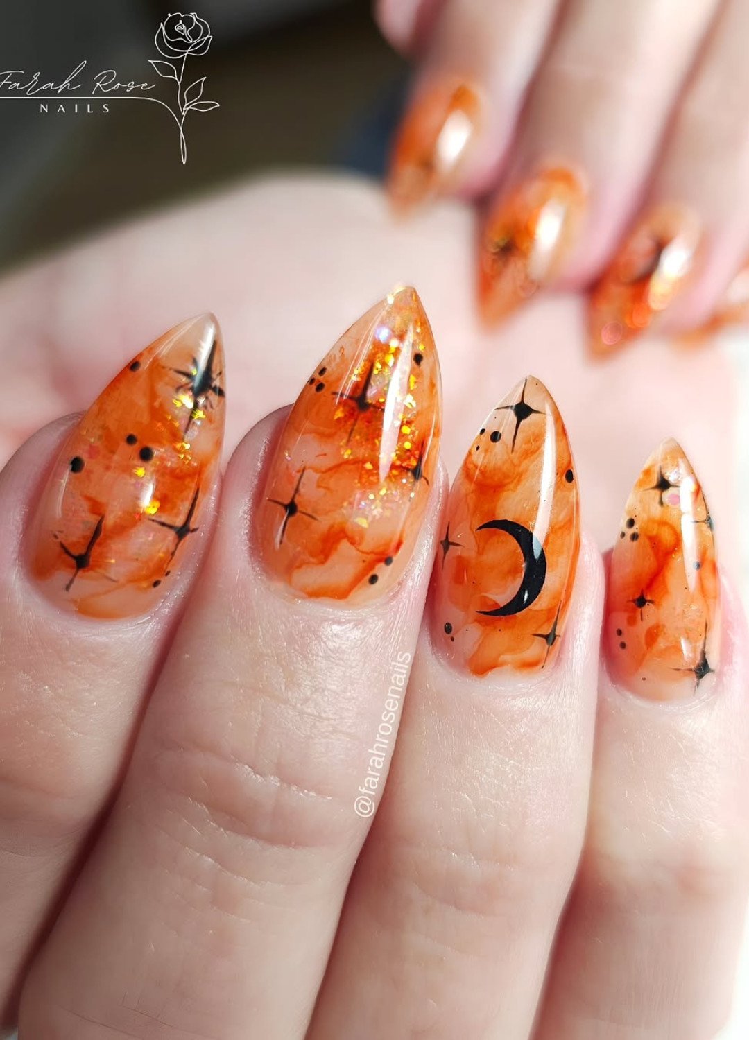 Display of Marble nails with orange flames, glitter and black midnights instantly give spooky-season vibes.