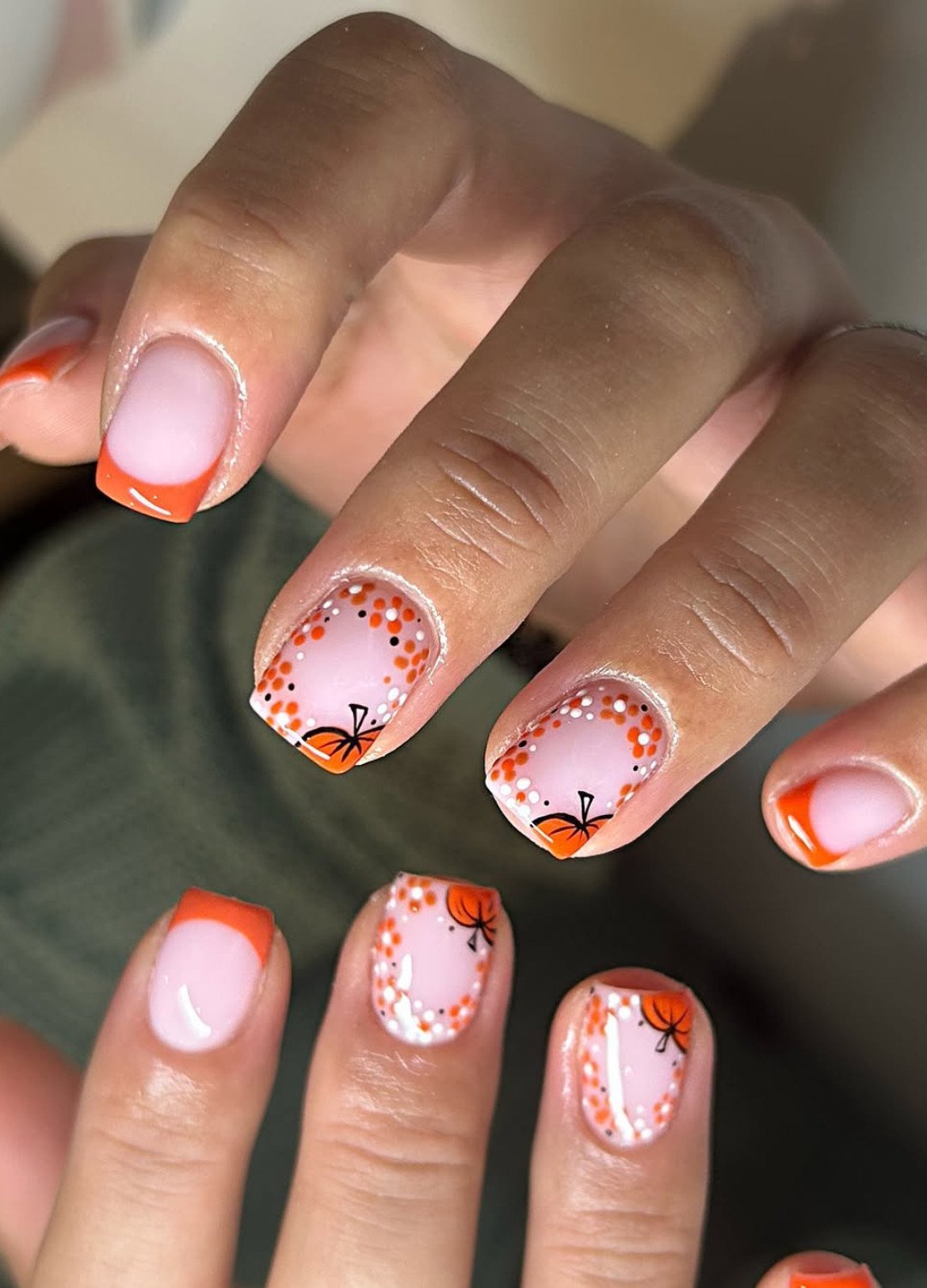Display of nails featuring tiny pumpkins and leafy vines painted around your nude base nails with French tips