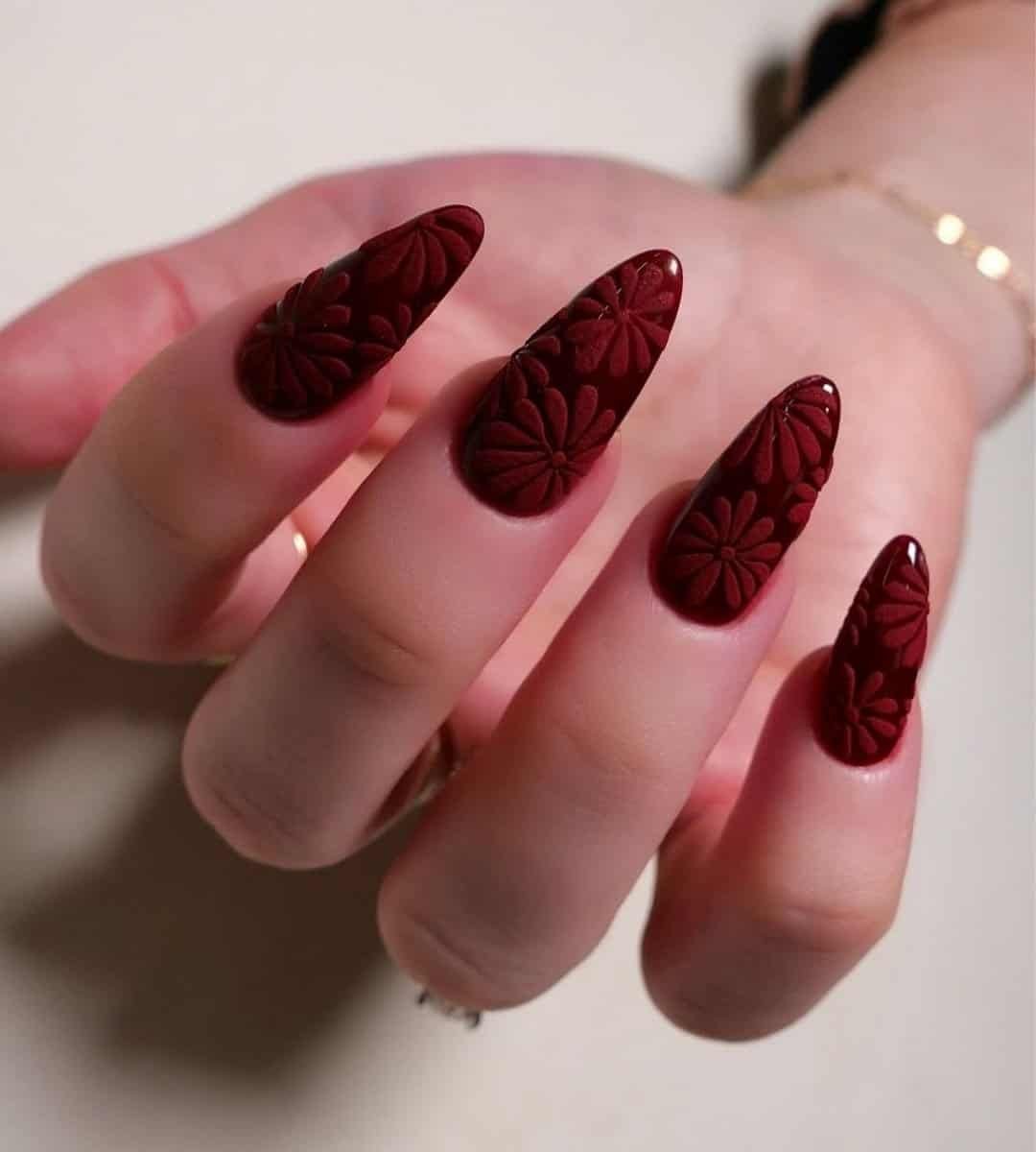 Image of Glossy nails with red base paired with subtle floral linework designs, like 3D, makes for an intellectual yet artsy vibe.